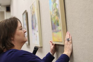 Marie Hull Gallery Director and Art Department Chair Melanie Atkinson hangs her work in preparation for the Faculty Art Show. The show begins on Nov. 9 at Hinds Community College.