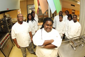 James Chapman, left foreground, and Durnitra Weeks, instructor in the Culinary Arts program at Hinds Community College's Utica Campus, stand in the kitchen with seven others enrolled in the program this past semester. (April Garon/Hinds Community College)