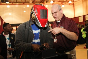 Rodrick Snow, left, a Raymond High School senior, takes a turn in a welding simulator while Industrial Maintenance Instructor Geoffrey Horne gives some assistance at Eagle Experience 2016 at Mayo Gym at the Raymond Campus Feb. 5, 2016. (April Garon/Hinds Community College)