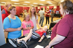 Alexis Vaughn, center foreground, speaks about the George Ball Simulation Center with support staff member Lesa McFarland at the Fall 2016 Nursing Showcase at Hinds Community College Jackson Campus-Nursing/Allied Health Center. From left, Vaughn's mother and sister, Marsha and Madison Vaughn. On the table is a manikin used to simulate various life functions in the simulation facility. (Hinds Community College/April Garon)