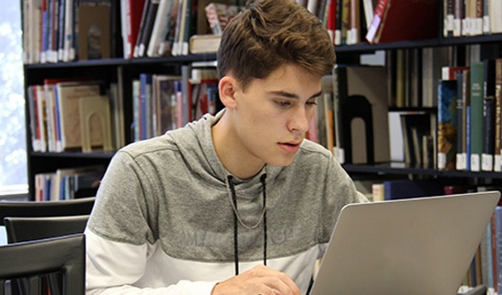 student on laptop in library
