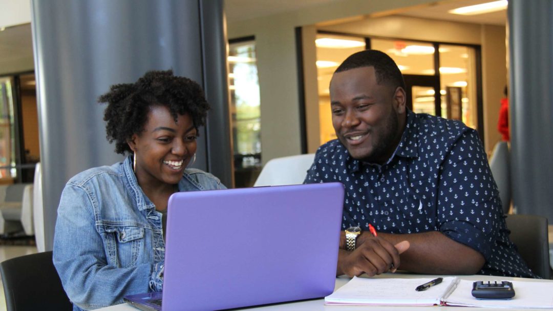 female and male looking at laptop together smiling